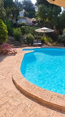 a large blue swimming pool with an umbrella at Superb sea view villa with pool and big garden in Pietrosella