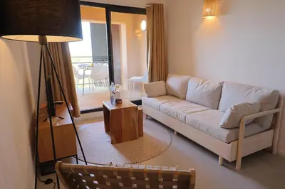 a living room with a couch and a table at L'Envol - T3 vue mer avec piscine et plage privée in Pianottoli-Caldarello