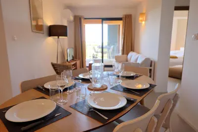 a dining room table with plates and glasses on it at L'Envol - T3 vue mer avec piscine et plage privée in Pianottoli-Caldarello