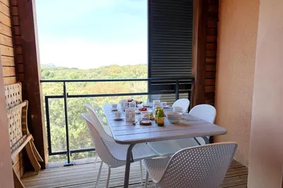 a table on a balcony with white chairs at L'Envol - T3 vue mer avec piscine et plage privée in Pianottoli-Caldarello