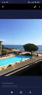 a view of a pool with the ocean in the background at appartement bords de Mer in Santa-Lucia-di-Moriani