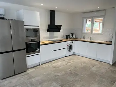 a kitchen with white cabinets and a washer and dryer at Chez lili in Ghisonaccia