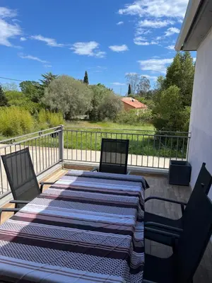 a patio with two chairs and a bed on a balcony at Chez lili in Ghisonaccia