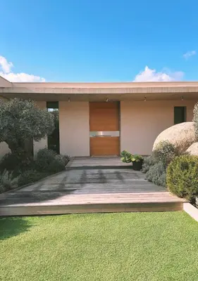 a house with a wooden door and a yard at Villa Anjo in Zonza