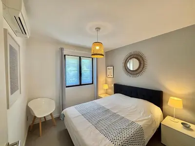 a bedroom with a bed and a table and a mirror at Appartement 26 les terrasses de l'isolella Porticcio in Porticcio