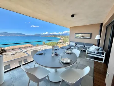 a dining room with a table and chairs and the ocean at Appartement 26 les terrasses de l'isolella Porticcio in Porticcio