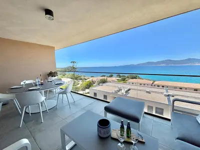 a balcony with a table and chairs and a view of the ocean at Appartement 26 les terrasses de l'isolella Porticcio in Porticcio