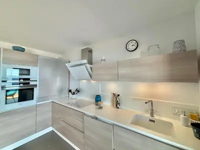 a kitchen with a sink and a clock on the wall at Appartement 26 les terrasses de l'isolella Porticcio in Porticcio
