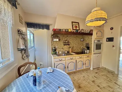 a kitchen with a table and a sink and a counter at Appartement Le Panoria sanguinaires Ajaccio in Ajaccio