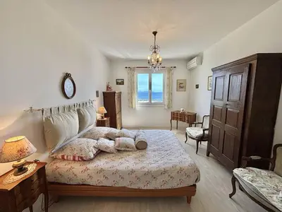 a bedroom with a bed and a table and a window at Appartement Le Panoria sanguinaires Ajaccio in Ajaccio