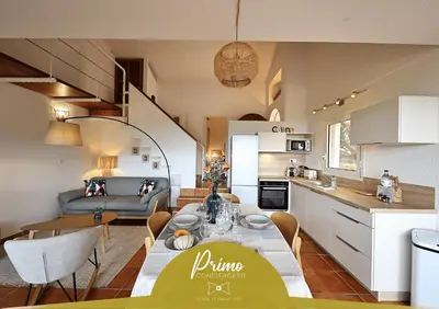 a kitchen and a living room with a table and a dining room at Sous le Pin - Villa paisible face aux îles Lavezzi in Bonifacio