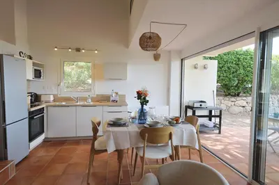 a kitchen and dining room with a table and chairs at Sous le Pin - Villa paisible face aux îles Lavezzi in Bonifacio