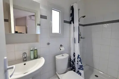 a white bathroom with a toilet and a sink at Sous le Pin - Villa paisible face aux îles Lavezzi in Bonifacio