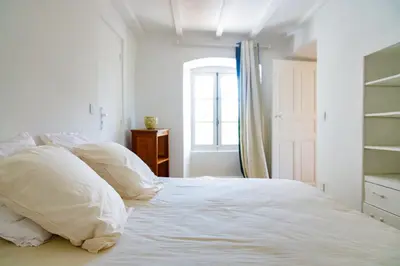 a white bed with white pillows and a window at U Vermentinu in Aghione