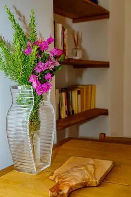 a clear vase with pink flowers sitting on a table at U Vermentinu in Aghione