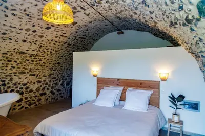a bedroom with a white bed with a stone wall at Suite du Domaine Marquiliani in Fautea