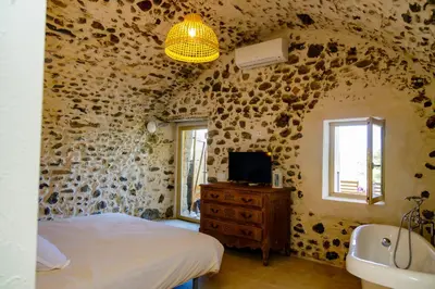a bedroom with a stone wall with a bed and a sink at Suite du Domaine Marquiliani in Fautea