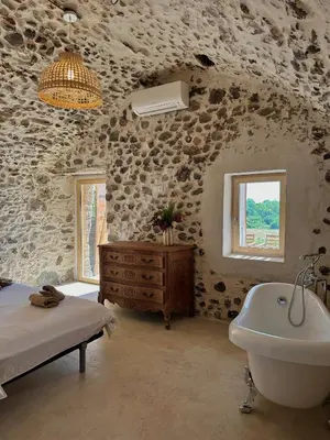 a stone walled bathroom with a tub and a sink at Suite du Domaine Marquiliani in Fautea