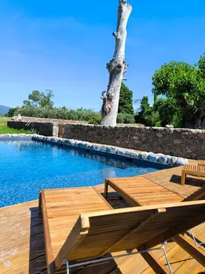 a wooden deck with a table and a swimming pool at Suite du Domaine Marquiliani in Fautea