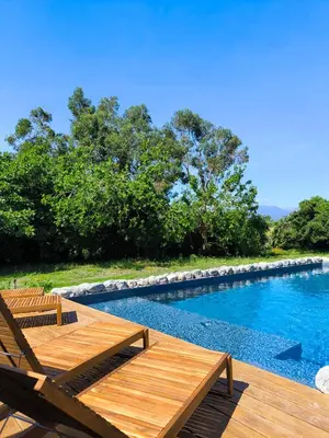 a swimming pool with a wooden deck and chairs at Suite du Domaine Marquiliani in Fautea