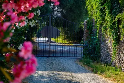 a gate to a driveway with pink flowers at Suite du Domaine Marquiliani in Fautea
