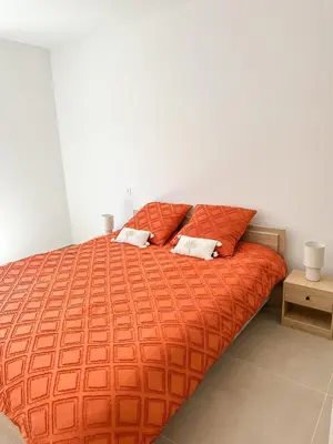 a bedroom with a orange bed with two pillows at Charmant T3 au coeur d'Ajaccio in Ajaccio