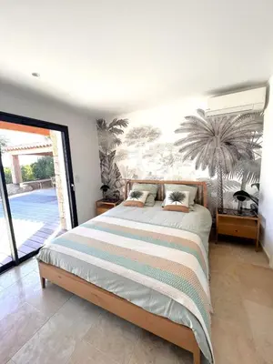 a bedroom with a bed and a palm tree mural at Casa Sarra Di Pinarello in Pinarellu