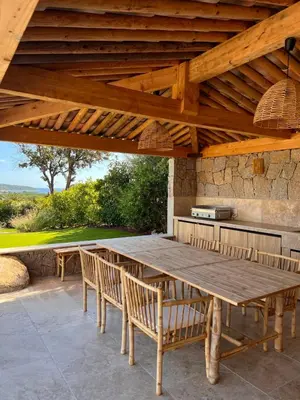 a wooden table and chairs under a wooden pergola at Casa Sarra Di Pinarello in Pinarellu