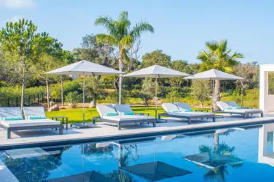 a swimming pool with lounge chairs and umbrellas at Villa Alimea San Ciprianu in Cirendinu