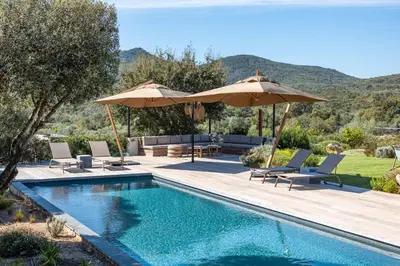 a swimming pool with umbrellas and chairs next to a swimming poolvisorvisor at Villa Alba Di Pinarello in Pinarellu