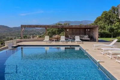 a swimming pool with lounge chairs next to a house at Villa Ghjiseppina Di Pinarello in Pinarellu