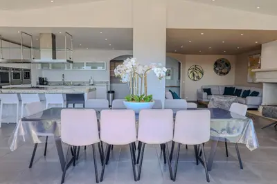a dining room with a glass table and white chairs at Villa Ghjiseppina Di Pinarello in Pinarellu