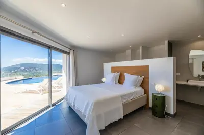a bedroom with a bed and a large window at Villa Ghjiseppina Di Pinarello in Pinarellu