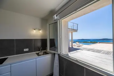 a kitchen with a sink and a large window at Villa Ghjiseppina Di Pinarello in Pinarellu