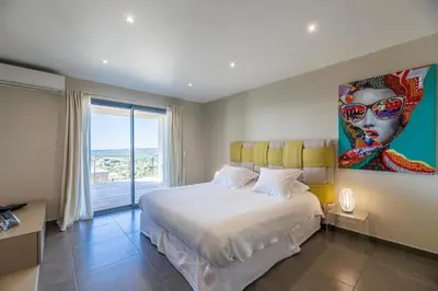 a bedroom with a bed with a painting on the wall at Villa Ghjiseppina Di Pinarello in Pinarellu