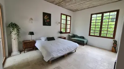 a bedroom with a bed and a couch and two windows at Maison - chambres d'hotes in Prunelli-di-Fiumorbo