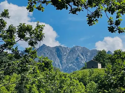 a barn on a hill with mountains in the background at CASA Marie-PAULINE in Sampolo