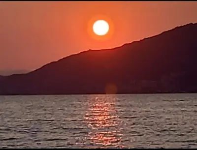 a sunset over a body of water with the sun at porticcio in Porticcio