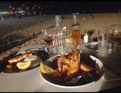 a table with a plate of seafood and drinks on the beach at porticcio in Porticcio