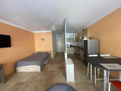 a bedroom with a bed and a table and a kitchen at charmant studio proche de la plage in Ajaccio