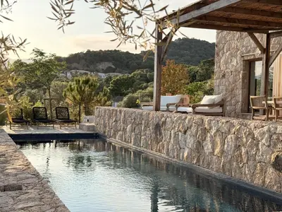 a stone retaining wall next to a swimming pool at Villa Sabbia in Lecci