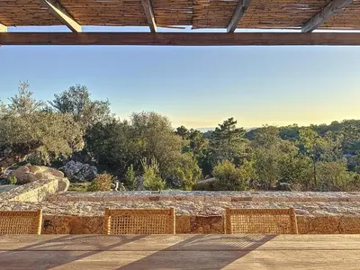 a patio with a stone wall and trees at Villa Sabbia in Lecci