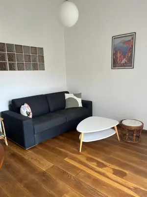 a living room with a black couch and a white table at T2 dans villa avec piscine in Porto-Vecchio