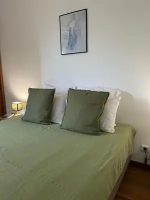 a bedroom with a bed with green sheets and pillows at T2 dans villa avec piscine in Porto-Vecchio