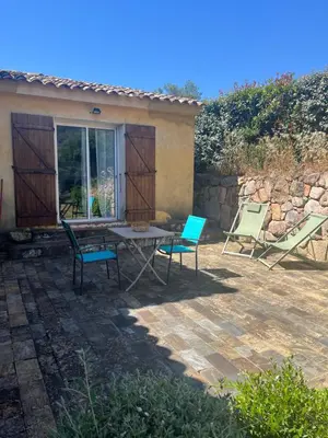 a patio with two chairs and a table and chairs at T2 dans villa avec piscine in Porto-Vecchio