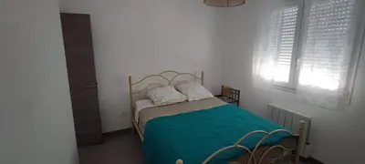 a bedroom with a bed with a green blanket and two pillows at Haut de villa in Cervione