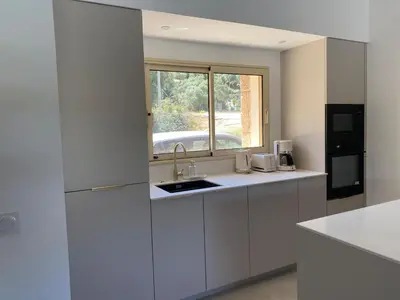a white kitchen with a sink and a window at Charming stone villa with pool in Figari