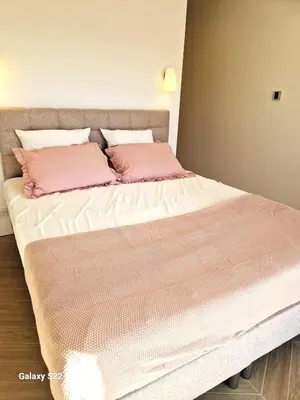 a bed with two pink pillows on top of it at Charming stone villa with pool in Figari