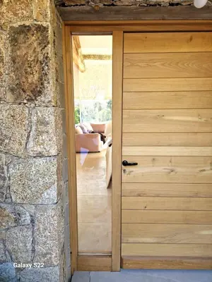 a wooden door in a room with a stone wall at Charming stone villa with pool in Figari