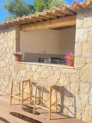 a stone wall with two stools on a patio at Charming stone villa with pool in Figari